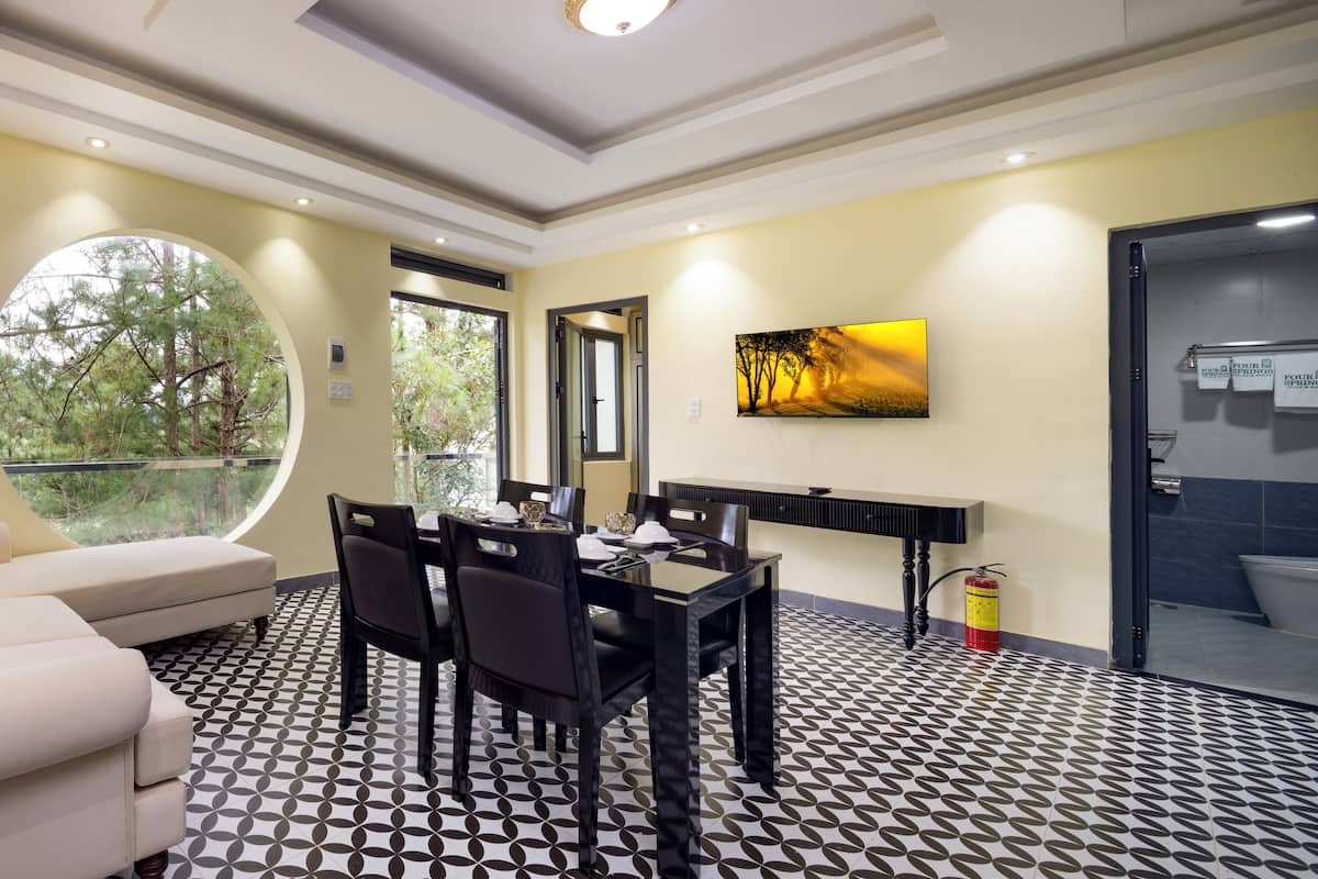A modern room with a round window, a dining area, and a painting on the wall.