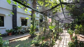 A garden area with potted plants, a pathway, and a building in the background. - OYO 93145 Pondok Alam Syariah (Depok)