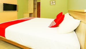 A neatly made bed with white and red bedding, a wooden headboard, and a small bedside table with a lamp. - OYO 93145 Pondok Alam Syariah (Depok)