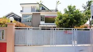 A gated residential area with a modern two-story house, a white fence, and a sign indicating no parking. - OYO 93145 Pondok Alam Syariah (Depok)