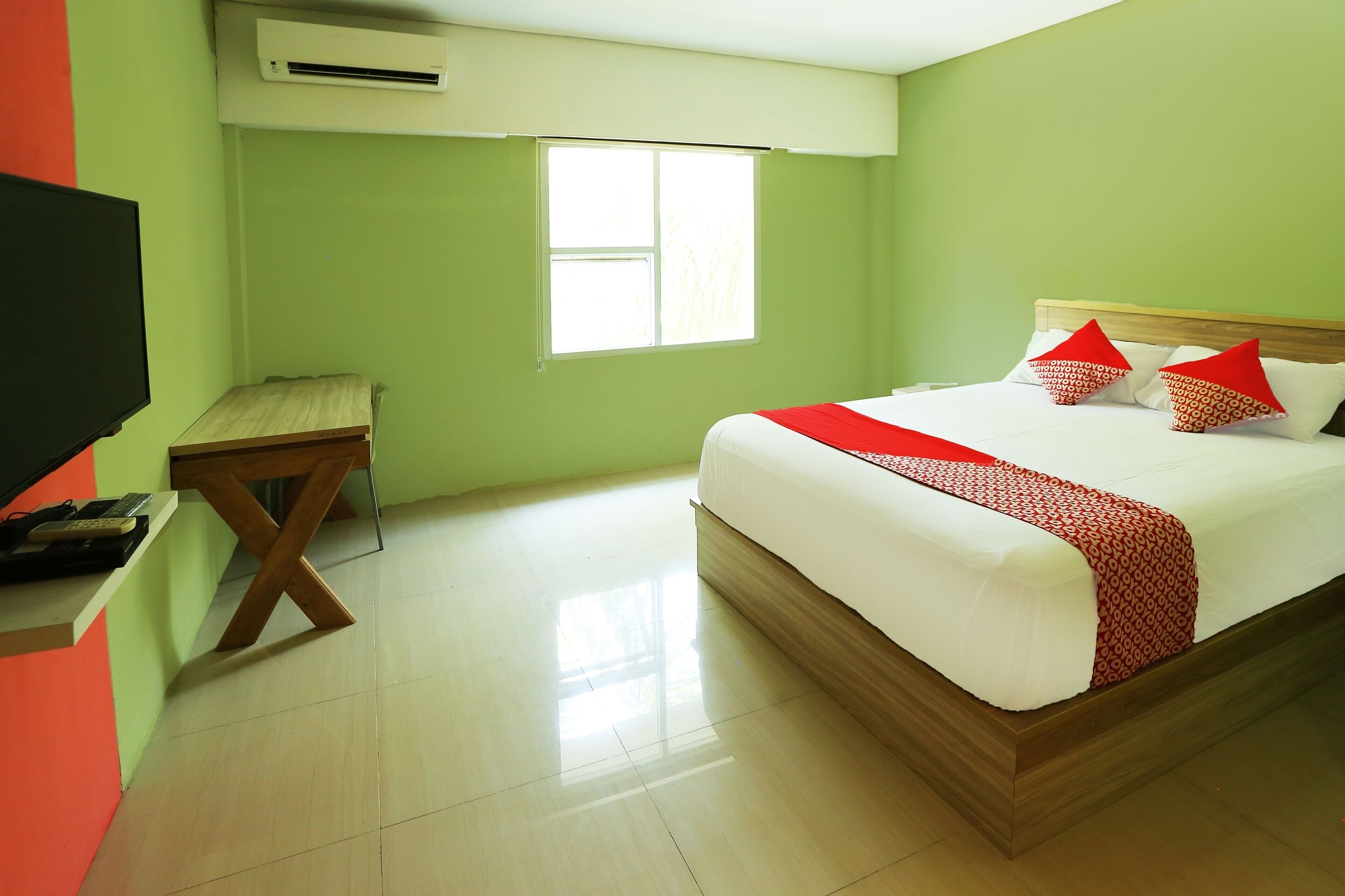 A hotel room with a bed, a desk, a television, and a window.