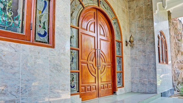 A grand wooden double door with intricate carvings, set in a hallway with marble walls and a tiled floor. - SPOT ON 93144 Homestay H. Syarif Syariah - Bandar Gresik 2 (Gresik)