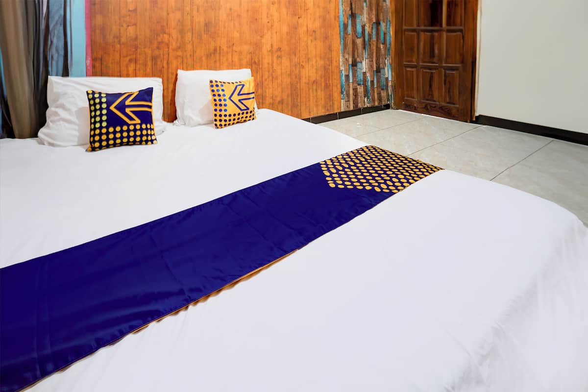 A neatly made bed with white linens and two decorative pillows with geometric patterns.