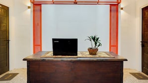 Ein hölzerner Empfangstresen mit einem Lenovo Laptop und einer Topfpflanze.