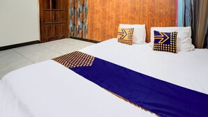 Ein ordentlich gemachtes Bett mit blauer und weißer Bettdecke, zwei Zierkissen und eine Holztür mit einem besonderen Design.
