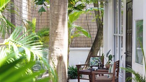 A patio with a wooden table and chairs, surrounded by lush greenery and a bamboo fence. - Babel Boutique Hotel (Siem Reap)