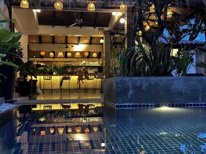 Un espace bar avec des sièges et une vue sur la piscine.
