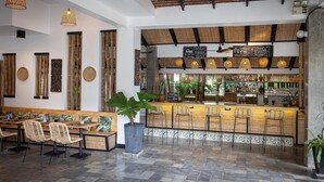 A bar area with a reception desk, seating, and a variety of plants. - Babel Boutique Hotel (Siem Reap)