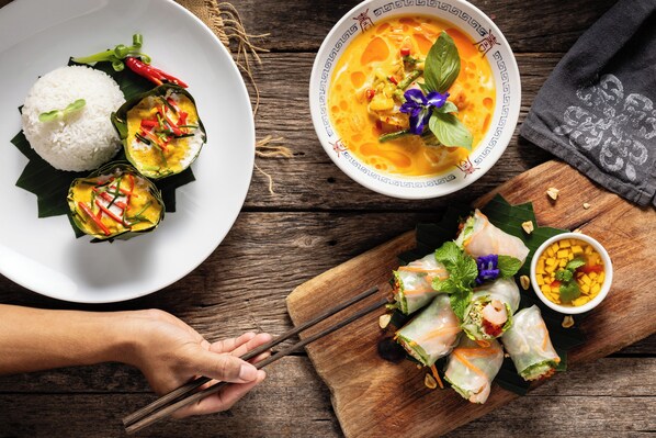 Une table avec un bol de soupe, du riz et des rouleaux de printemps.