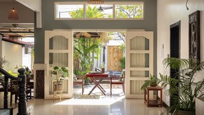 A spacious interior with a high ceiling, a staircase, and a large open doorway leading to an outdoor area with plants. - Babel Boutique Hotel (Siem Reap)