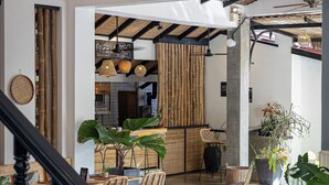 A spacious indoor area with a staircase, wicker furniture, and hanging pendant lights. - Babel Boutique Hotel (Siem Reap)