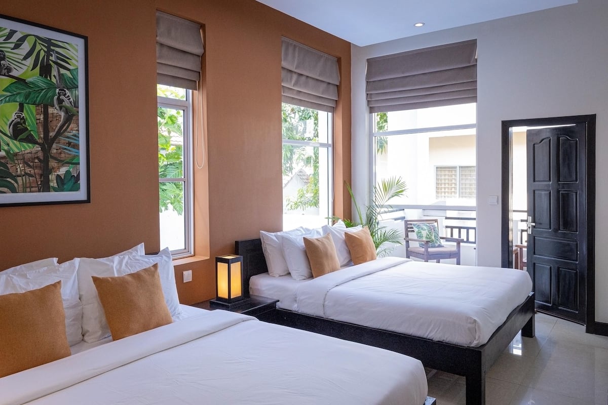 Een hotelkamer met twee bedden, een groot raam met uitzicht en een schilderij aan de muur.