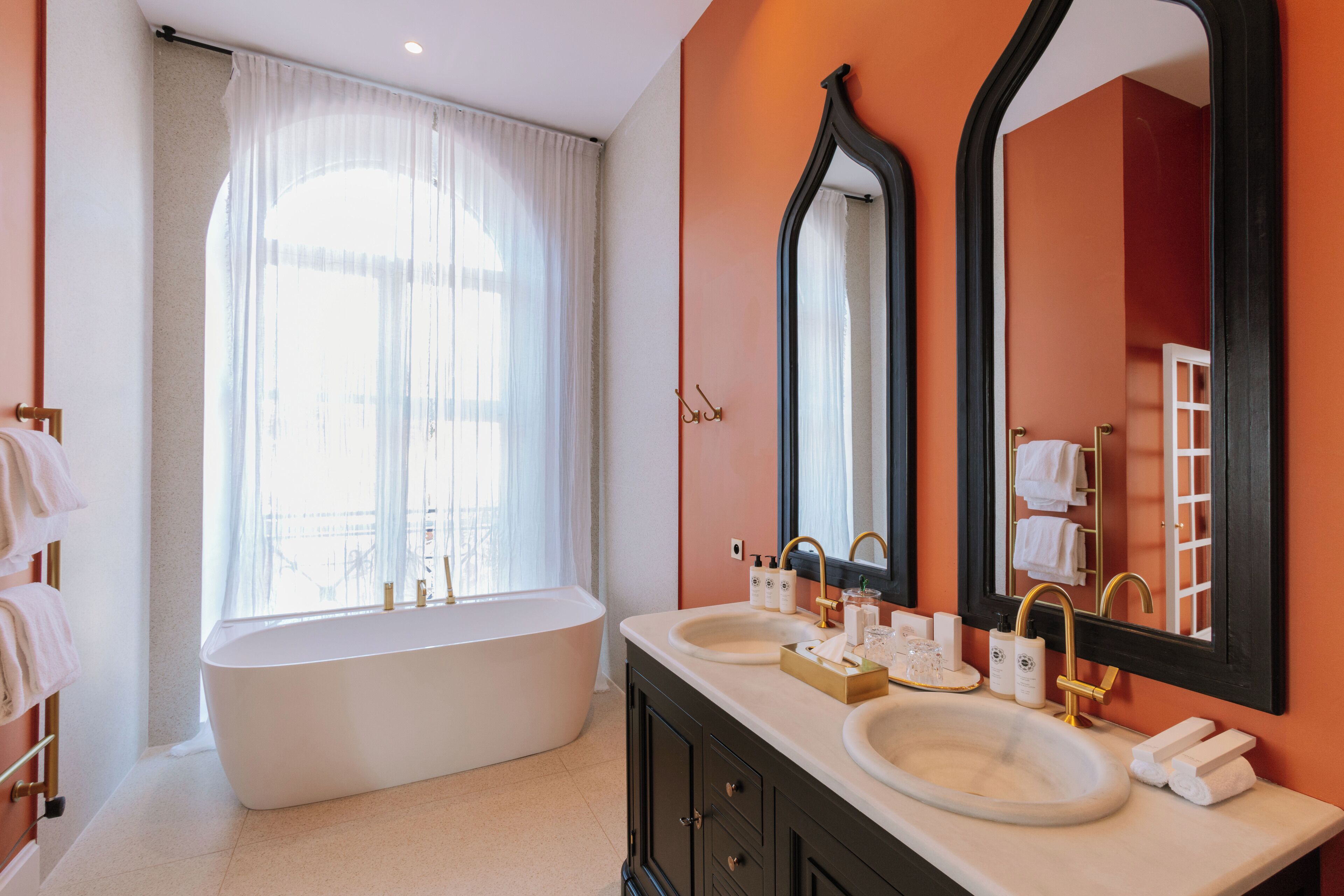 Un baño moderno con una bañera independiente, lavabos dobles y un espejo grande.