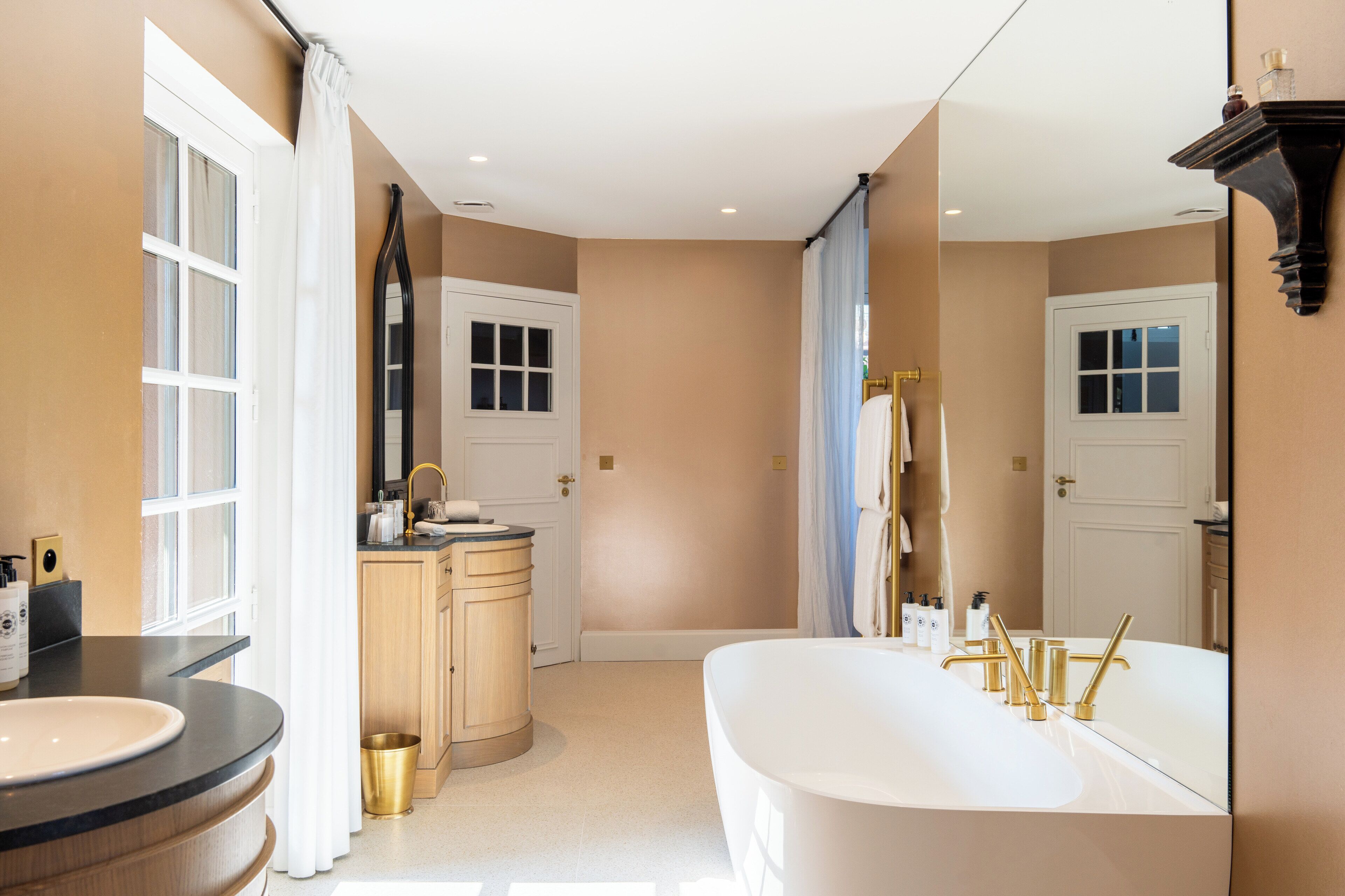 A modern bathroom with a freestanding bathtub, a vanity with a sink, and a large mirror.