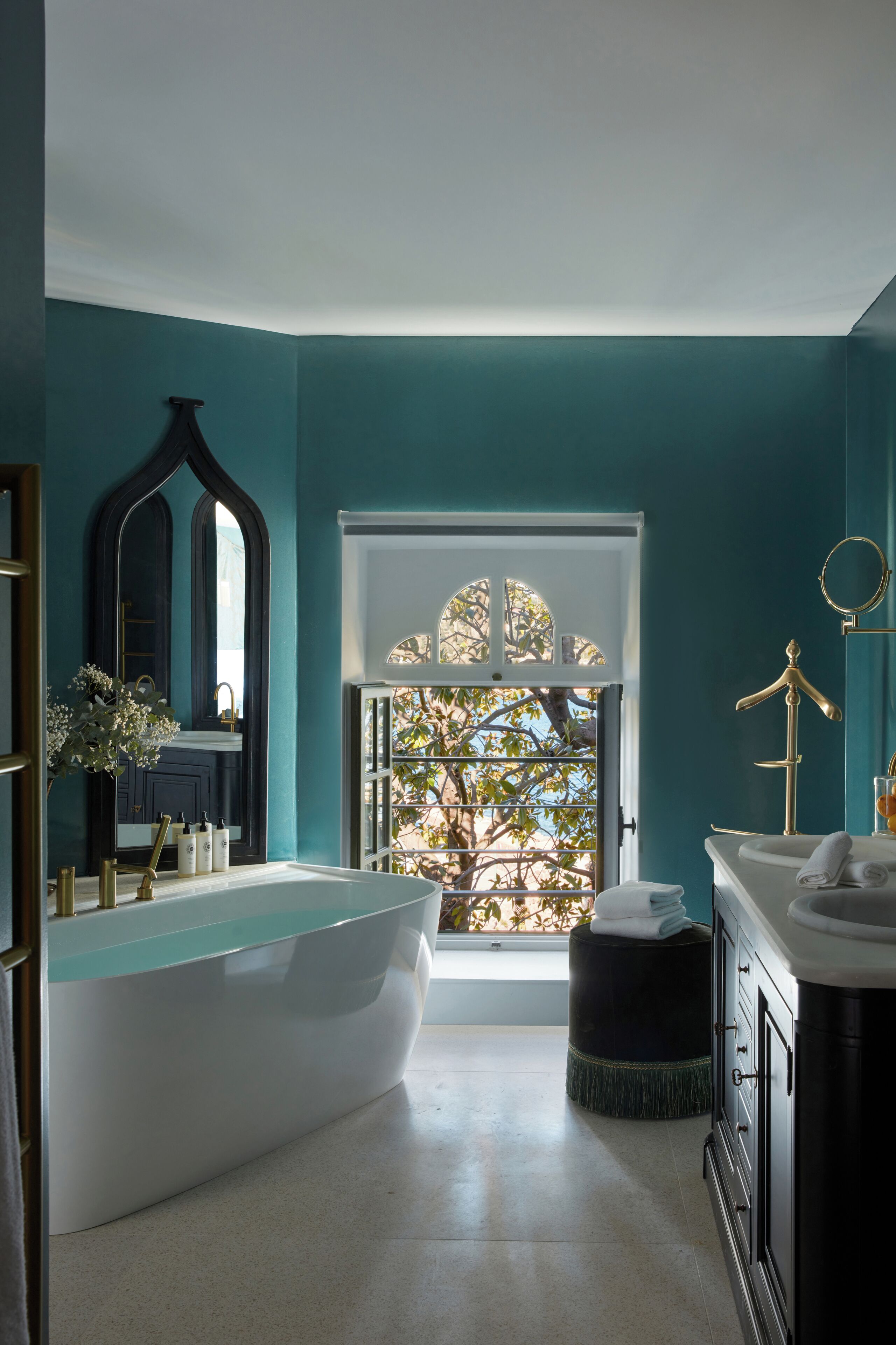 A bathroom with a freestanding bathtub, a large mirror, and a window with a view of trees.