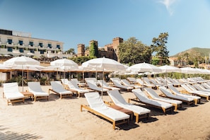 Aan een privéstrand, ligstoelen, parasols, strandlakens