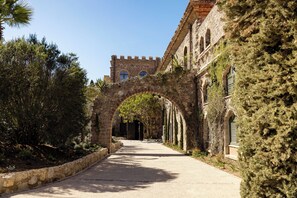 An arched pathway leading to a historic building with stone walls and a tower.