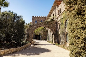 Un sendero arqueado que conduce a un edificio histórico de paredes de piedra y una torre.