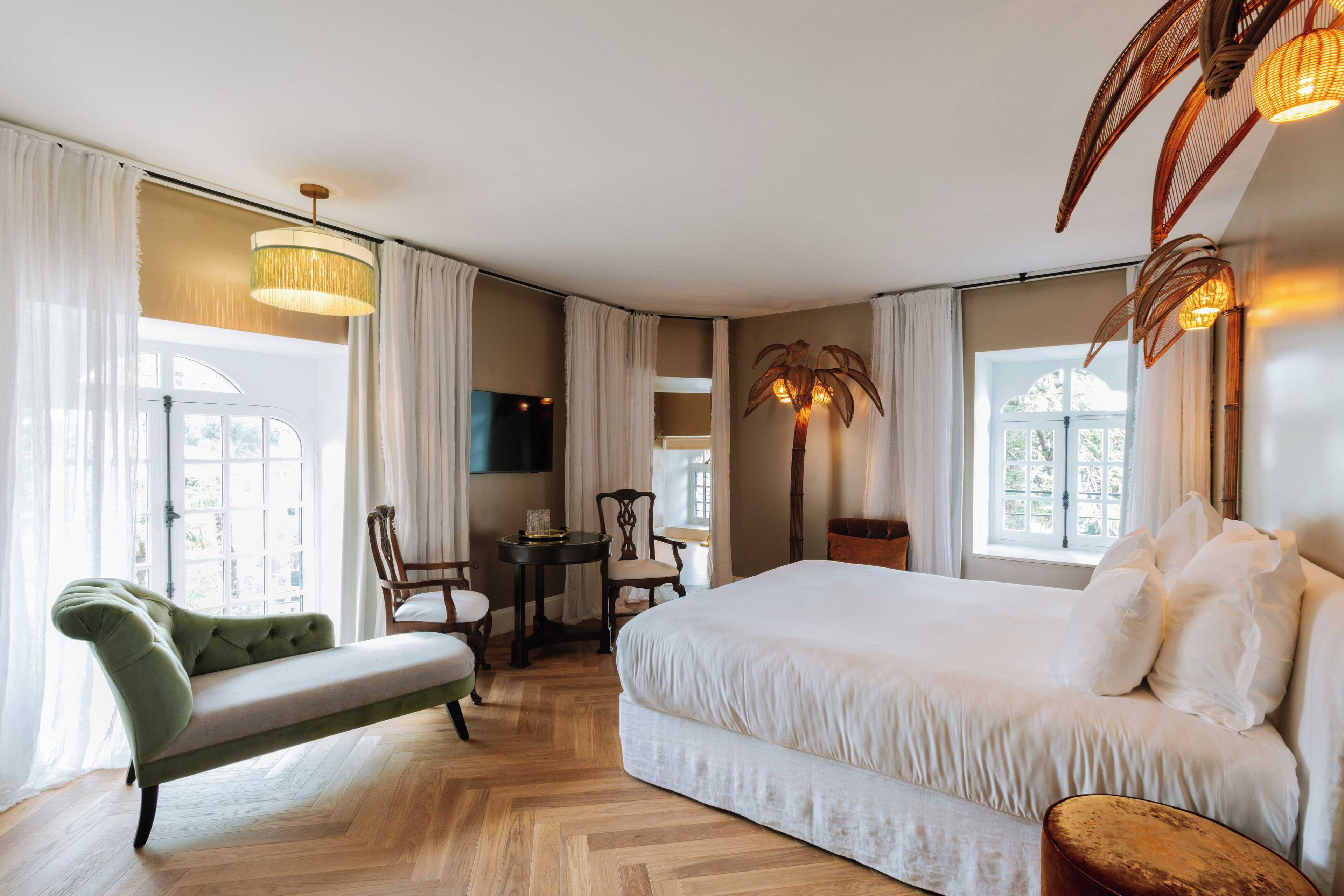 Un dormitorio con una cama grande, un sofá verde, una mesita y un televisor.