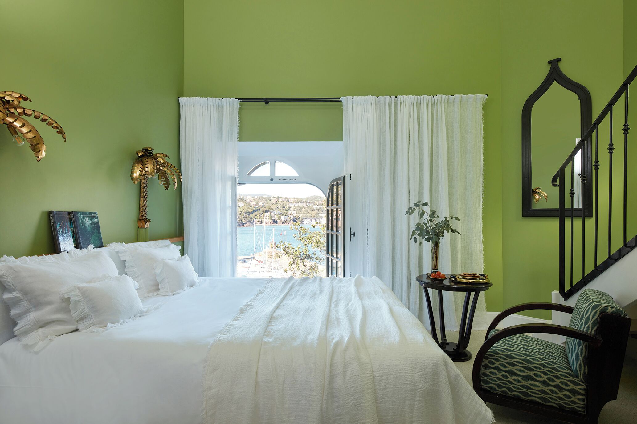 Une chambre à coucher avec un lit, une chaise, une table et une vue sur l’extérieur.