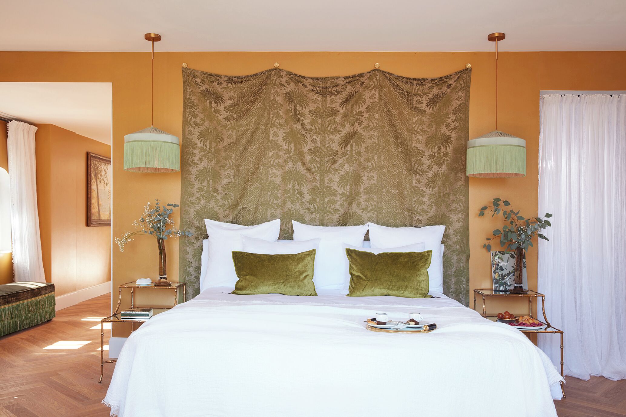 A neatly arranged bedroom with a large bed, two bedside tables, and a hanging light fixture.