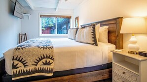 A neatly arranged bedroom with a bed, bedside table, and a window. - Atelier Allure - 2BD Mountain View + FREE Resort Amenities (Sun Valley)