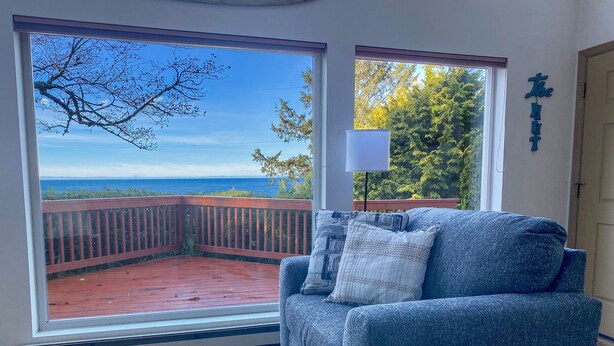 Una habitación con un amplio ventanal corredero que da a una terraza exterior con vista al océano.