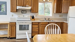 Una cocina con armarios de madera, una estufa blanca, un lavabo y un ventanal.