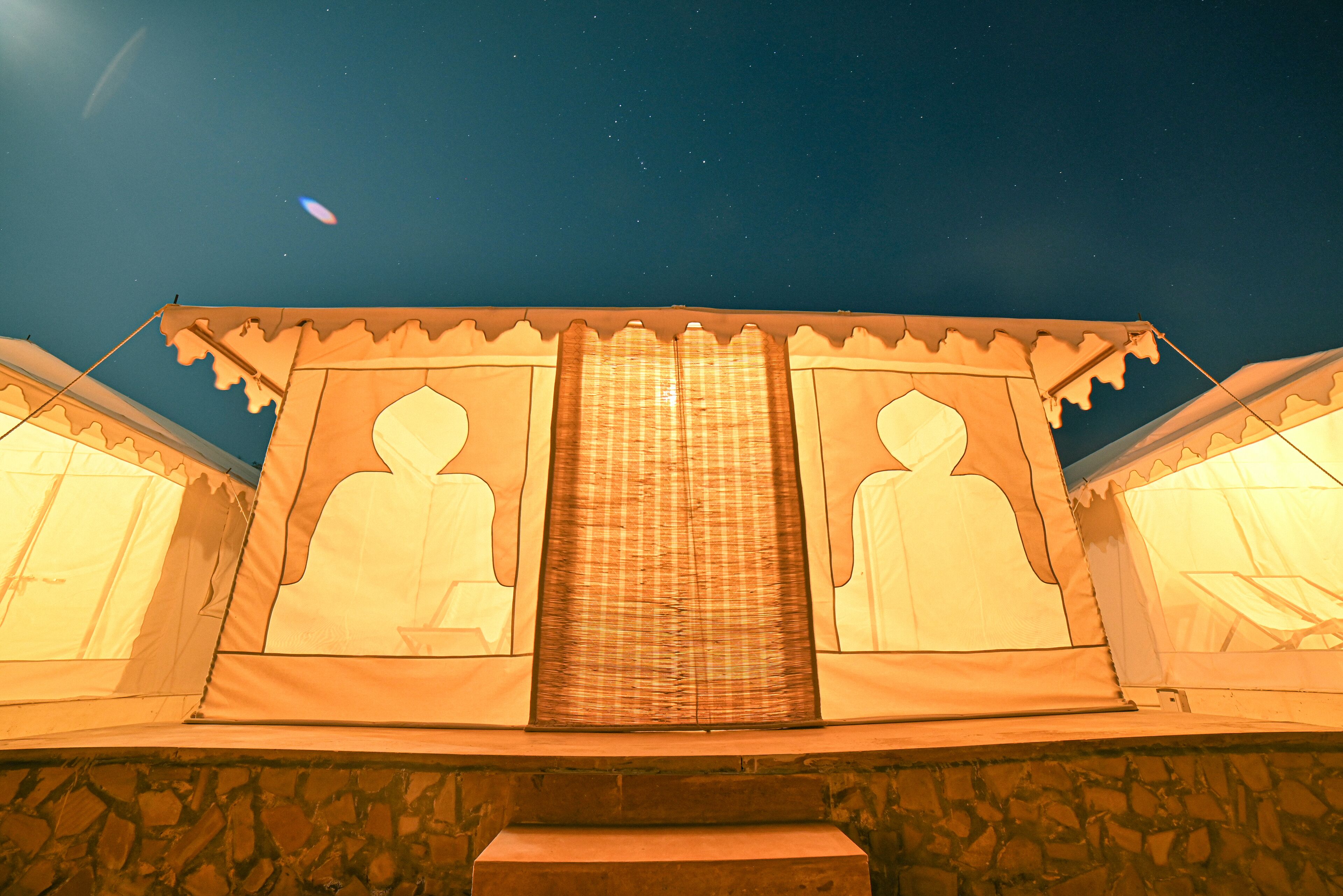 A night view of a building with a central structure featuring a large window and two symmetrical sides with similar designs.