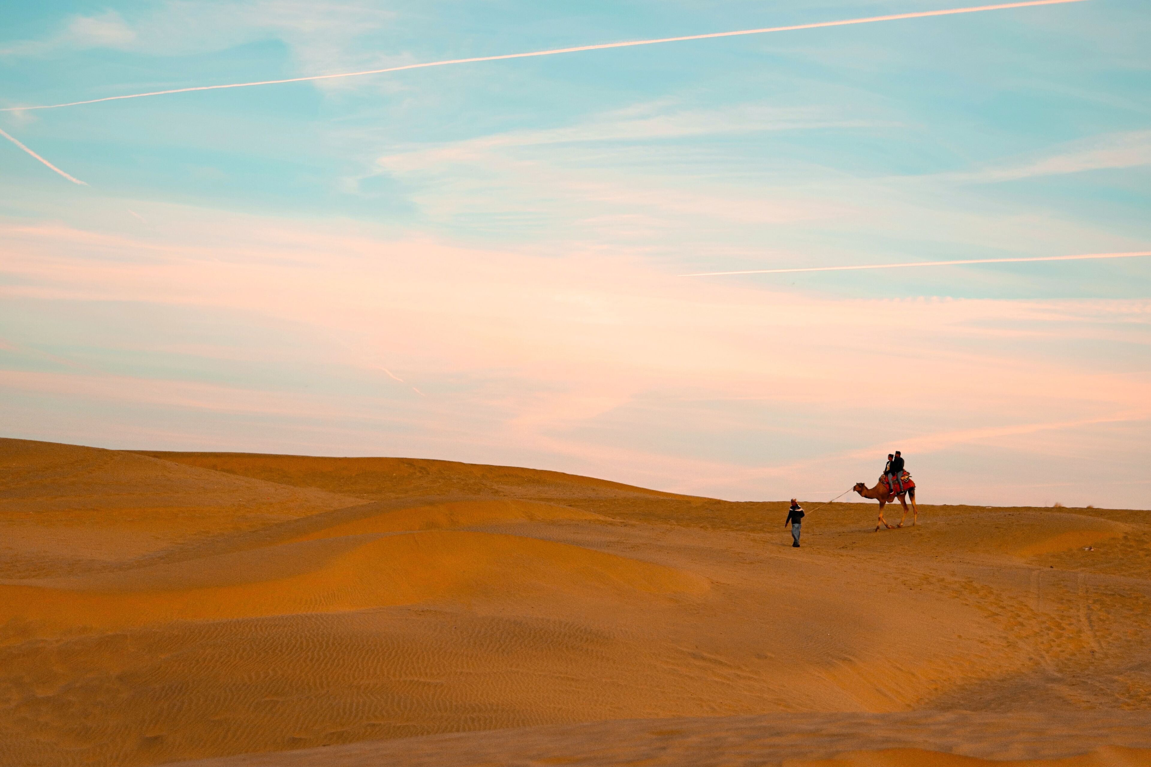 A desert landscape with sand dunes and a camel caravan.
