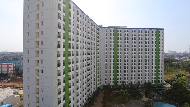 A high-rise building with multiple balconies, a swimming pool, and a landscaped garden area.