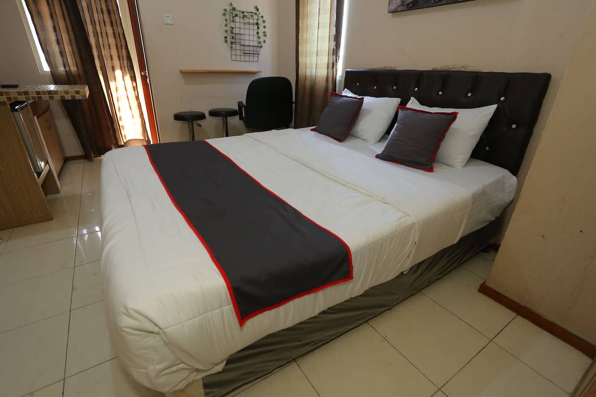 A neatly made bed with a black and white bedspread, a black headboard, and two pillows.