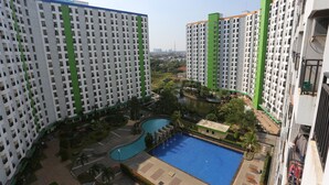 A high-rise residential building with multiple balconies, a swimming pool, and a landscaped courtyard.