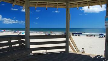 A wooden beach shelter with a view of the beach and ocean.