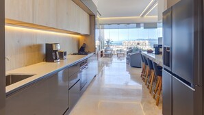 Une cuisine moderne dotée d’appareils électroménagers en acier inoxydable, de meubles en bois et d’une grande fenêtre offrant une vue sur la ville.