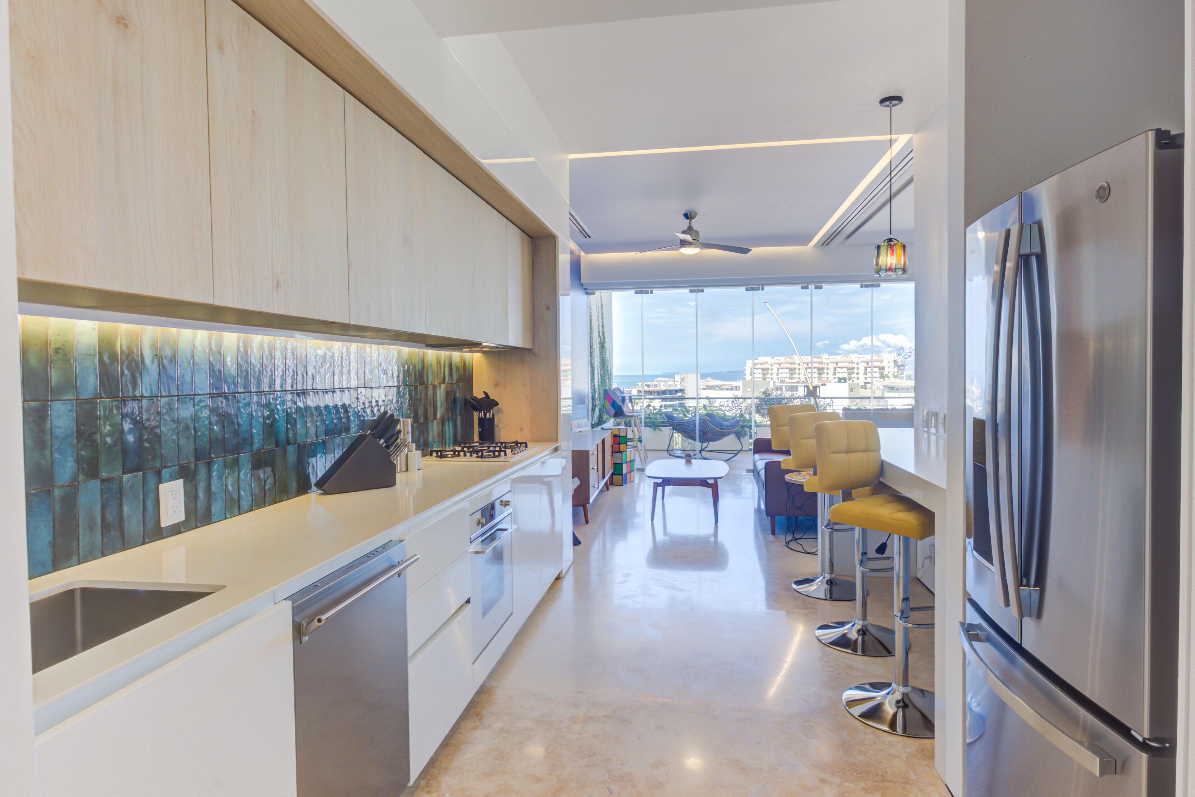 Une cuisine moderne avec vue sur la ville, un coin repas avec des tabourets de bar et un grand réfrigérateur.