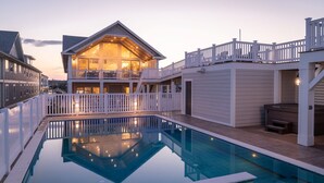 A two-story house with a swimming pool, white railings, and a hot tub. - Island Enchantment - Oceanfront Pet Friendly w/ Cabana Service (Kill Devil Hills)