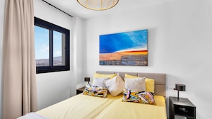 Une chambre moderne avec un grand lit, un tableau représentant un paysage urbain et une vue par la fenêtre.
