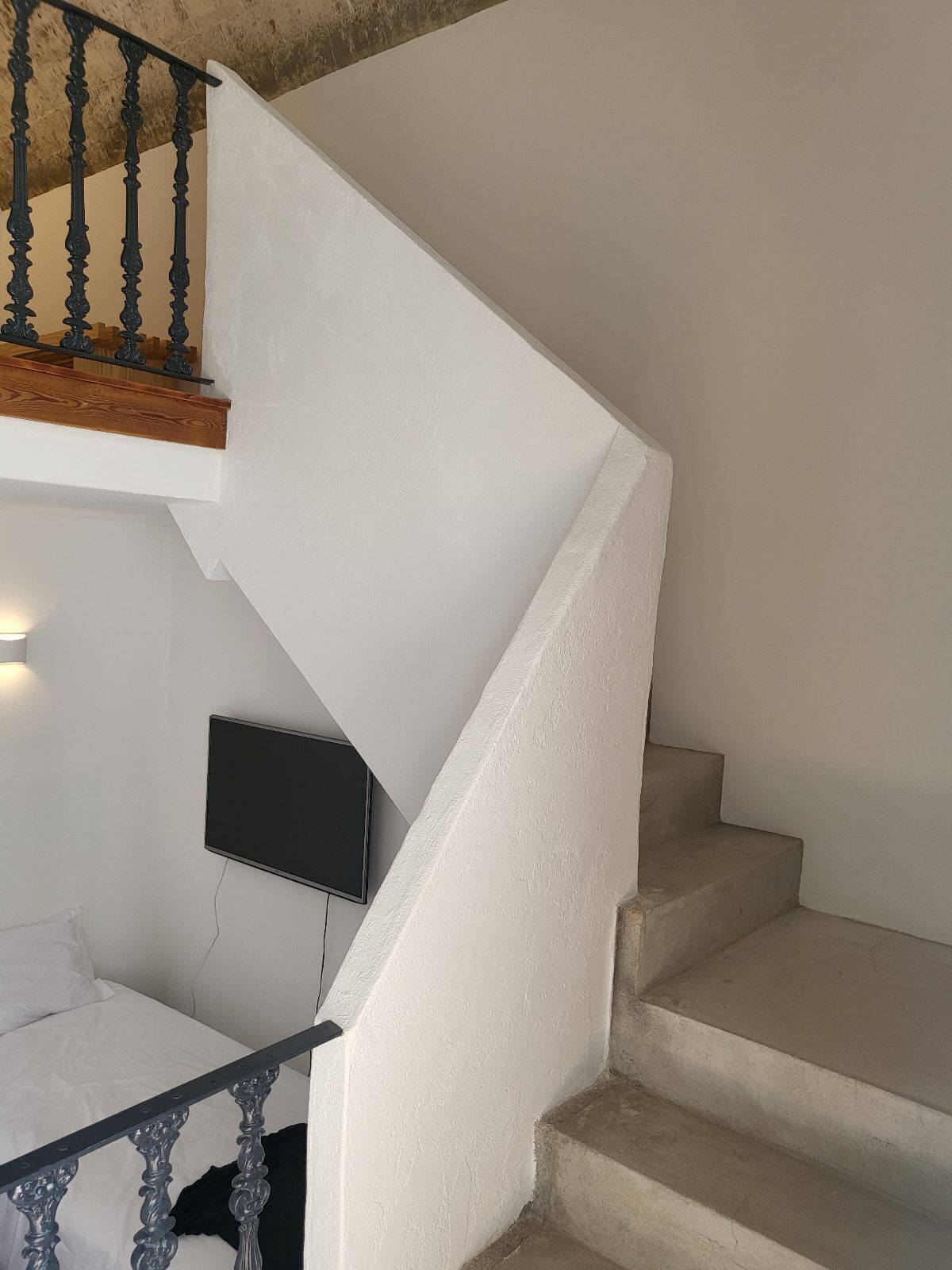 A staircase with a white wall and a wooden handrail.