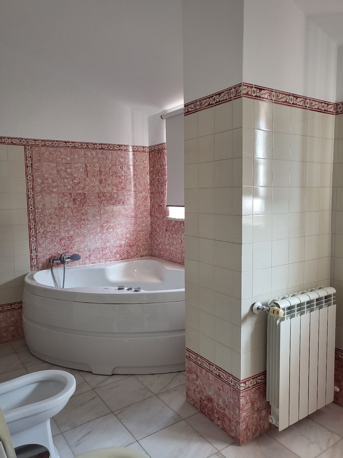 A bathroom with a bathtub, a toilet, and a radiator.