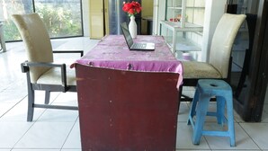 Una habitació amb un ordinador portàtil damunt d'una taula, dues cadires, un ram de flors i un tamboret.