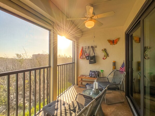 A balcony with a table and chairs, a ceiling fan, and decorative items including a gecko and an American flag.