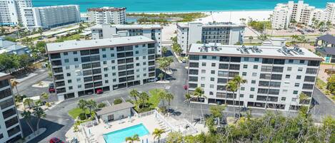 A high-rise hotel with multiple floors, a rooftop pool, and a view of the beach.