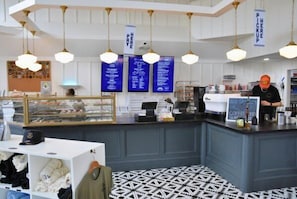 Un café moderno con mostrador, pizarras con la carta y suelo estampado.
