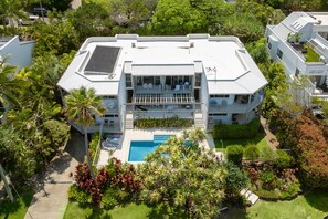 Residents enjoy balconies and a tranquil courtyard with a swimming pool surrounded by lush greenery.