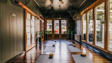 A hallway with wooden floors, large windows, and hanging light fixtures.