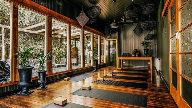 A wooden interior with large windows, a wooden table, and potted plants. - The Amalfi 20 bedrooms, exclusive use (Hepburn Springs)