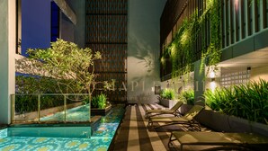 Uma área de piscina no terraço com espreguiçadeiras e plantas em vasos.