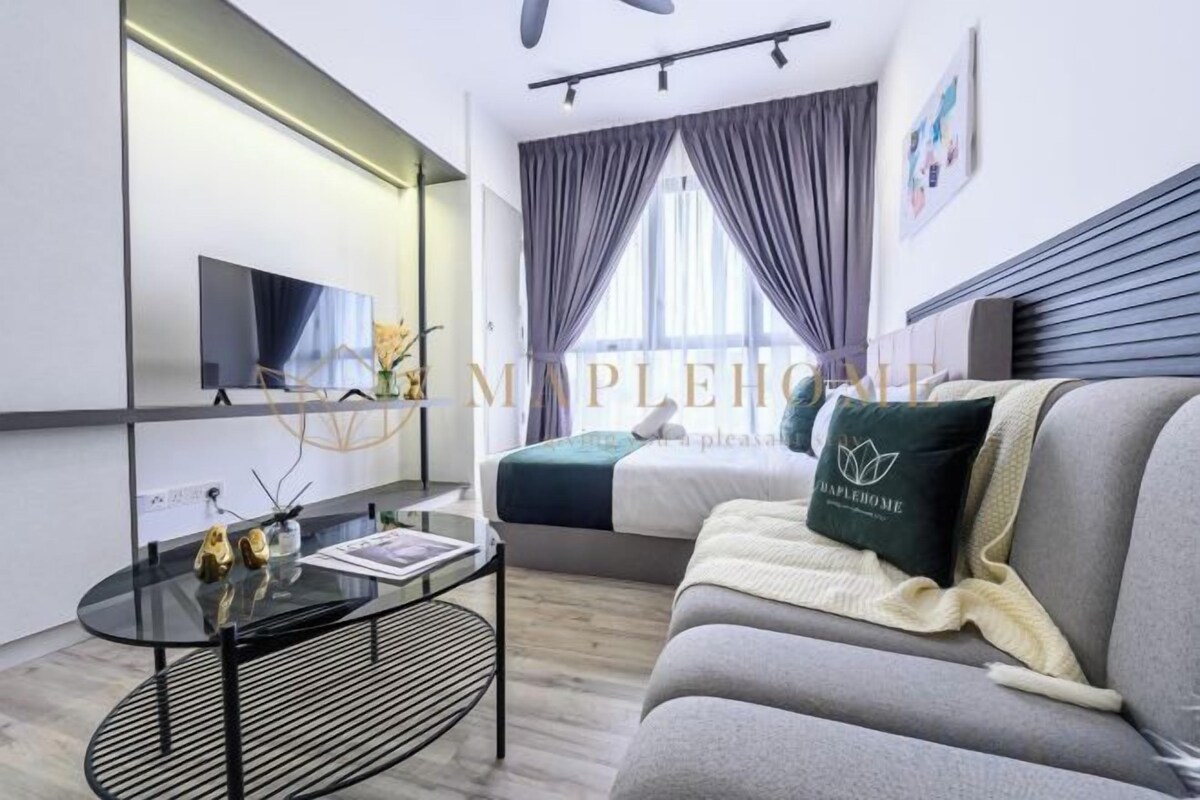 Una habitación de hotel moderna con cama, sofá, televisor y una mesita con objetos decorativos.