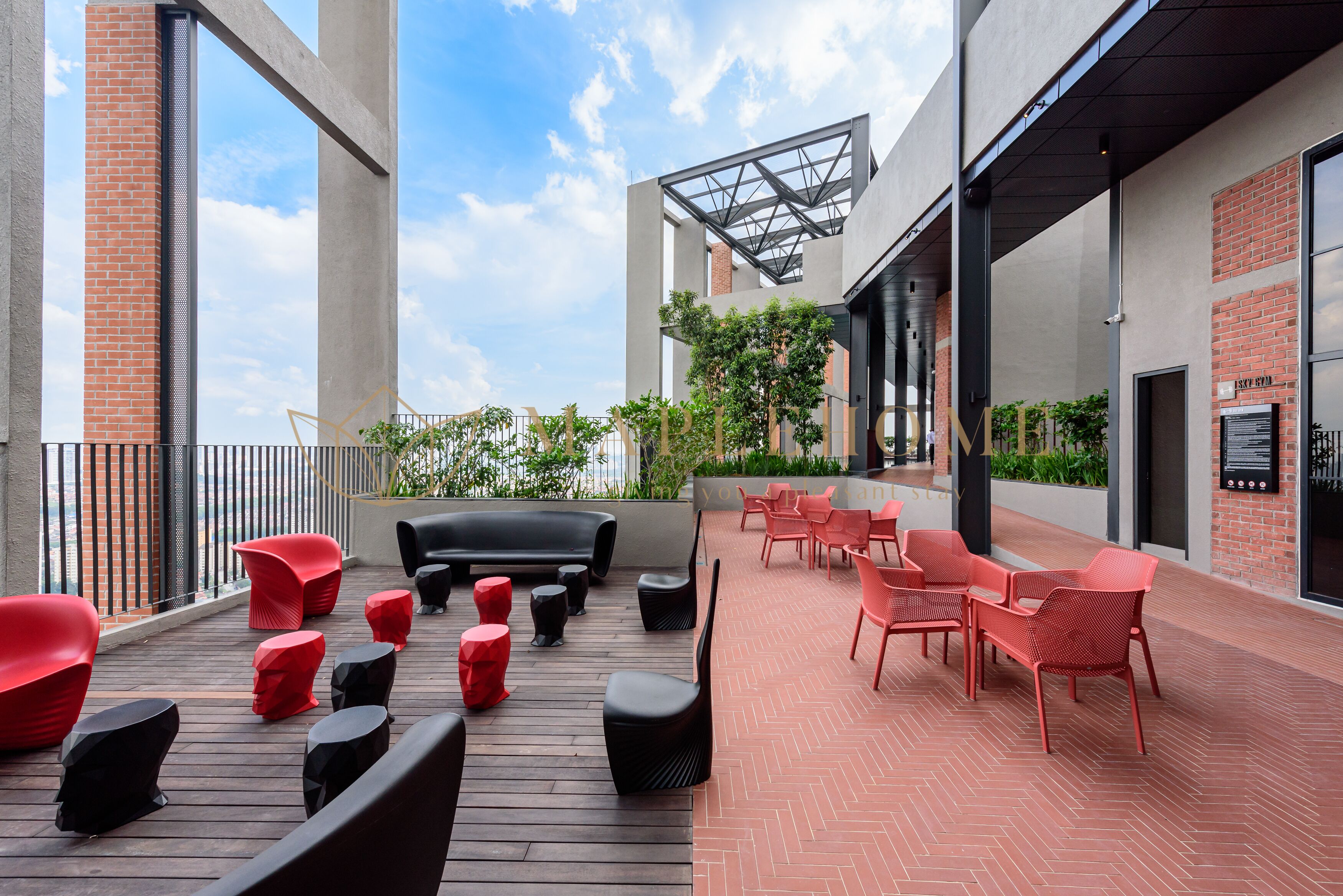 Un patio al aire libre con asientos rojos y negros, una terraza de madera y un muro de ladrillo.